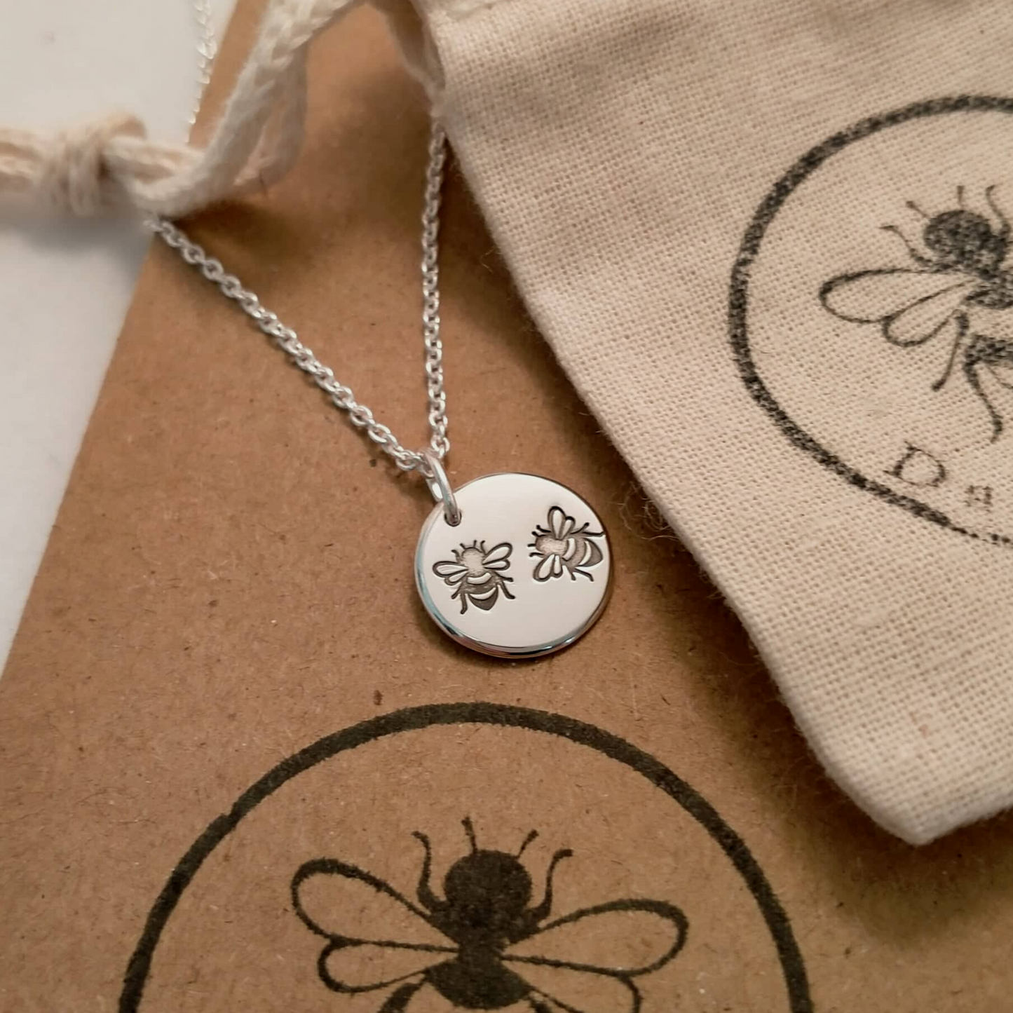 Bee stamped pendant with organic calico pouch.