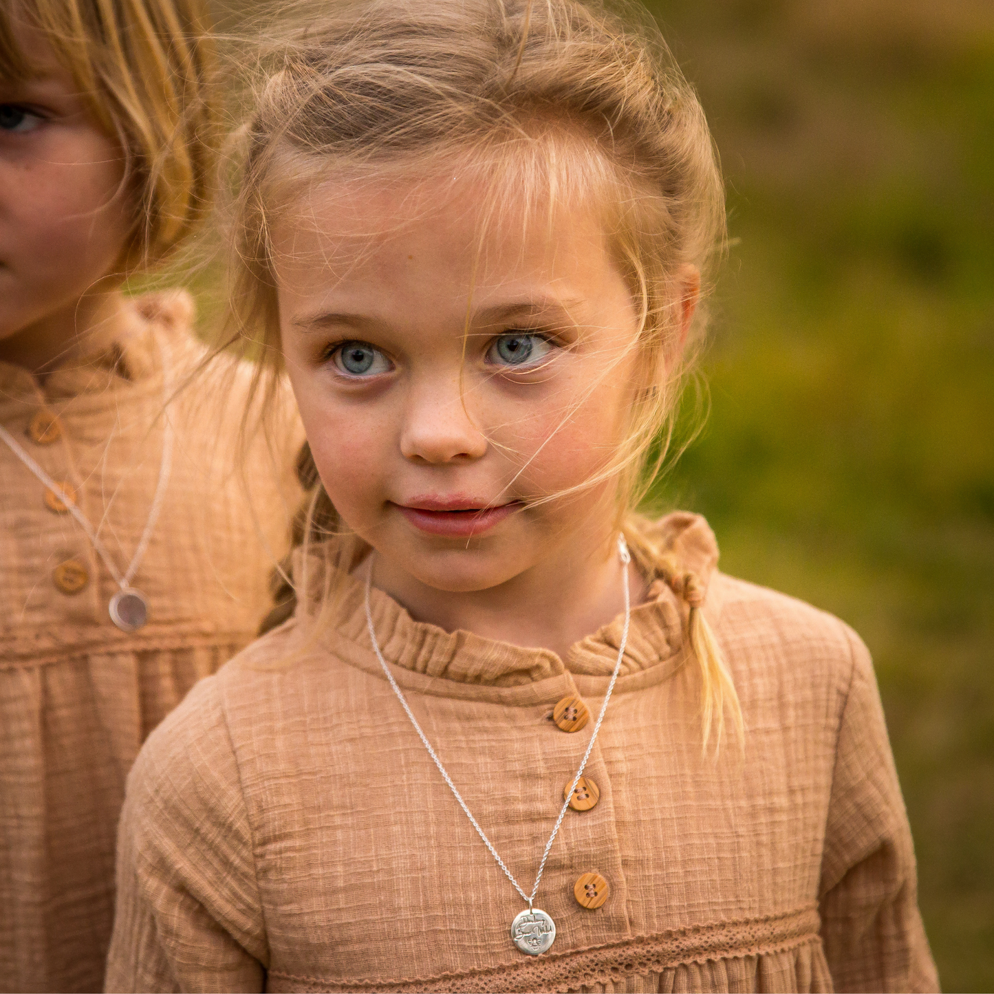 Girl wearing sterling silver disc pendant with words stamped on it; Darling, Bee Wild.