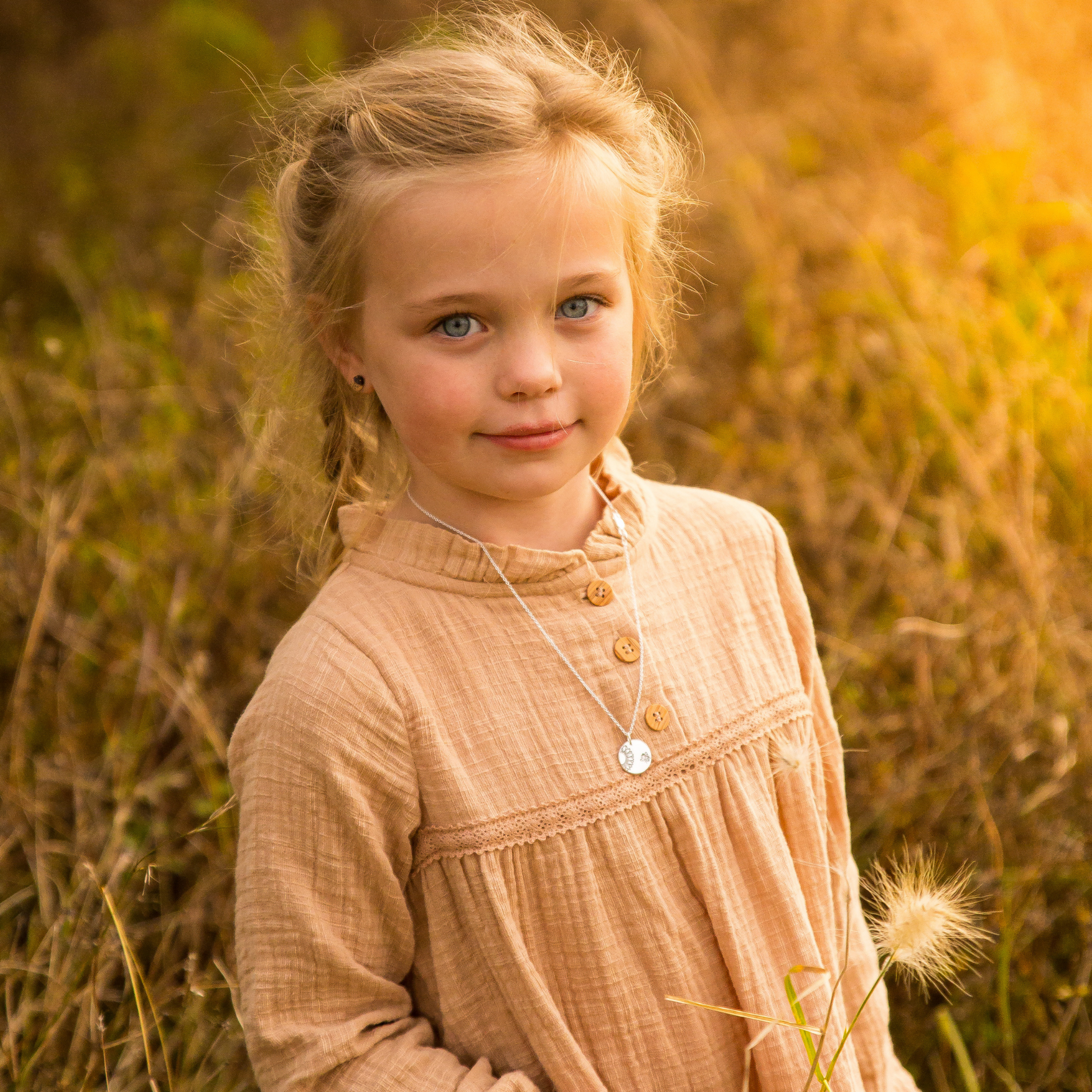 Sunflower and bee pendant worn by girl sitting in field